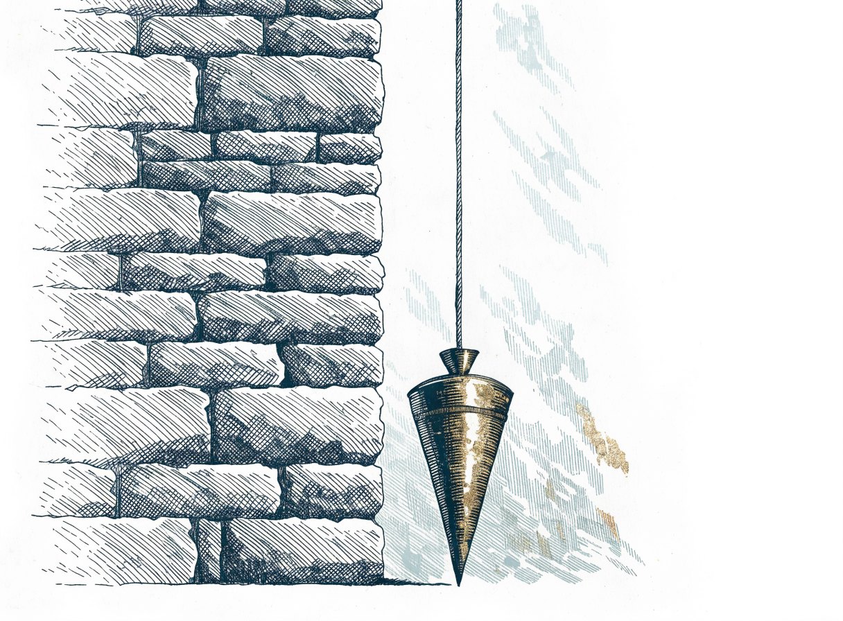 A bronze plumb bob hanging still on a taut cord beside a new stone wall
